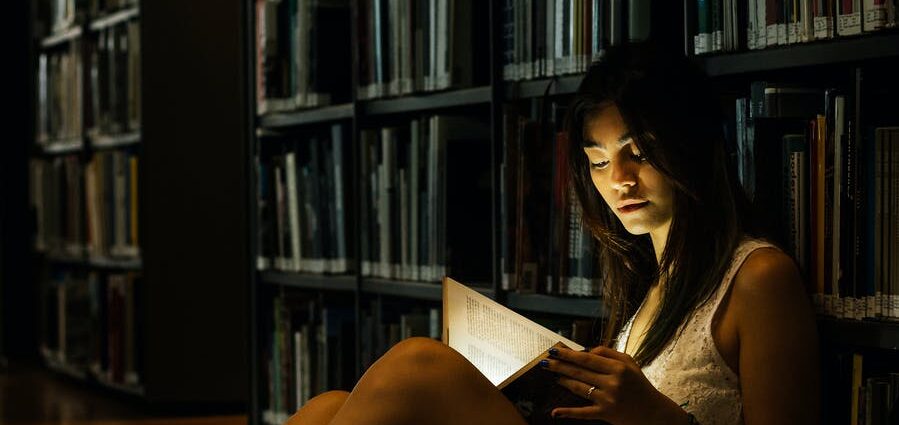 woman leaning on bookshelf
