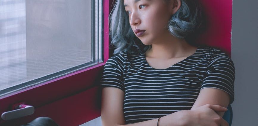 woman in black and white striped shirt while looking out at the window