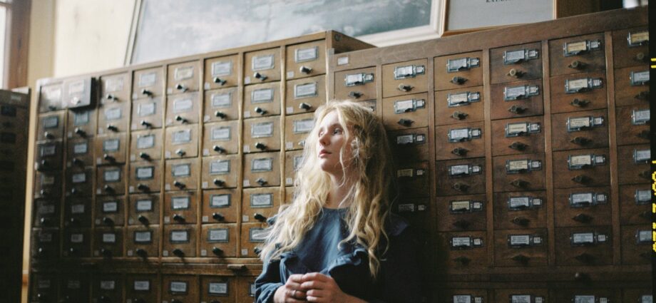 woman in blue long sleeve dress standing beside brown wooden cabinet