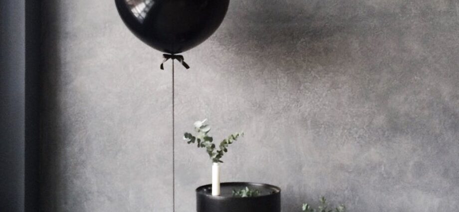 grayscale photography of balloon beside chanel metal barrel