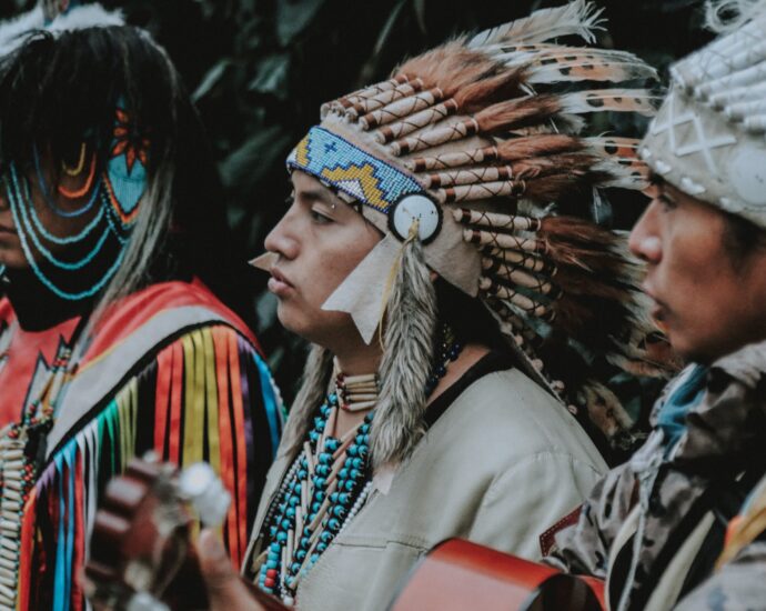 portrait of three men in traditional native american clothes playing guitar