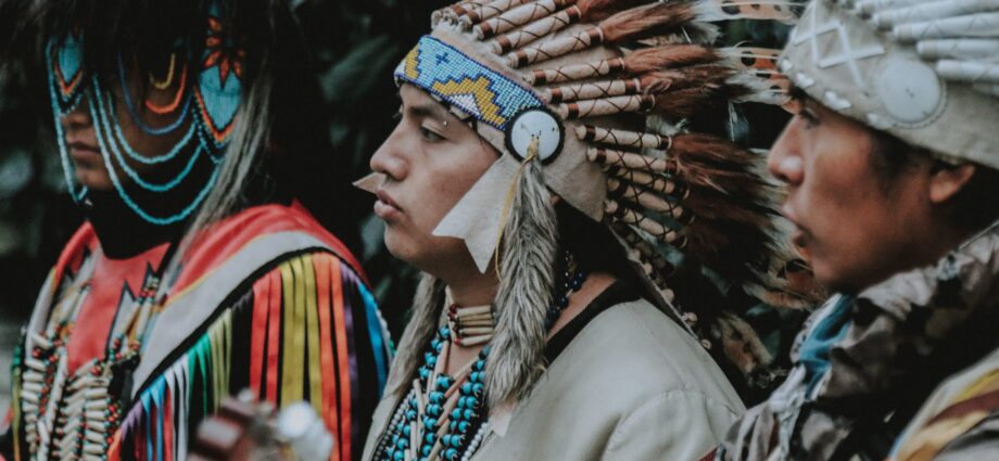 portrait of three men in traditional native american clothes playing guitar