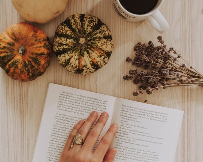 top view of a woman s hand on a book beside a coffee mug on a table