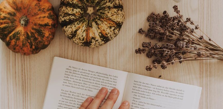 top view of a woman s hand on a book beside a coffee mug on a table