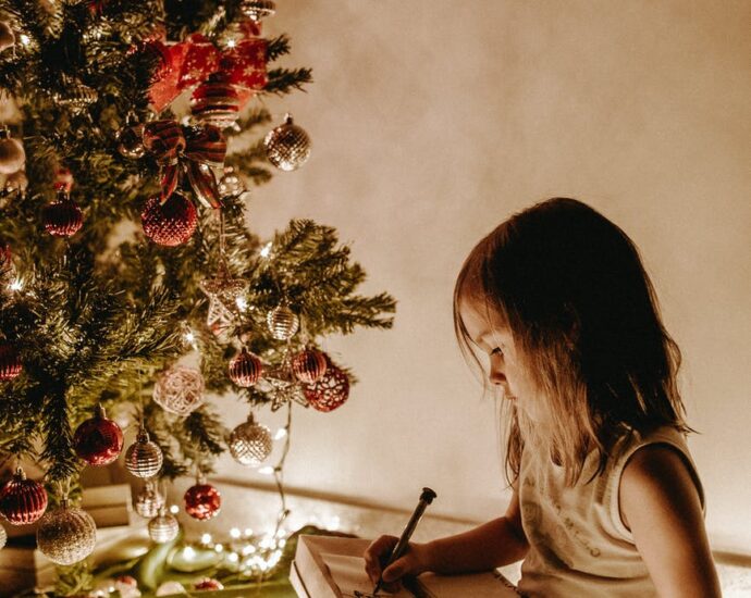 photo of girl sitting near christmas tree
