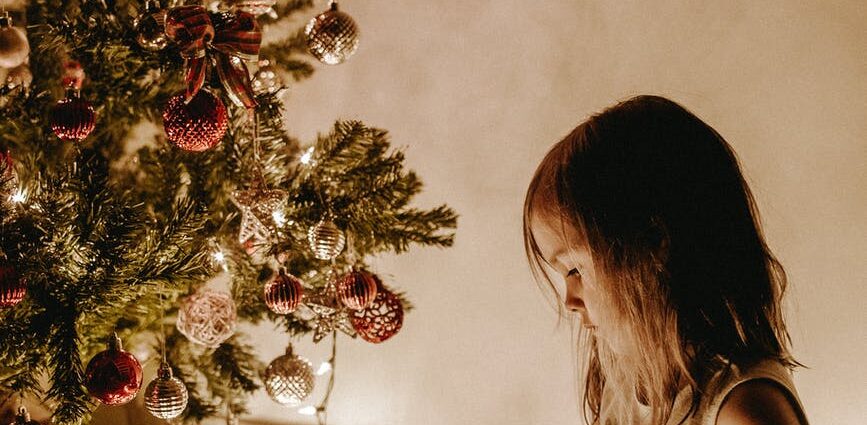 photo of girl sitting near christmas tree