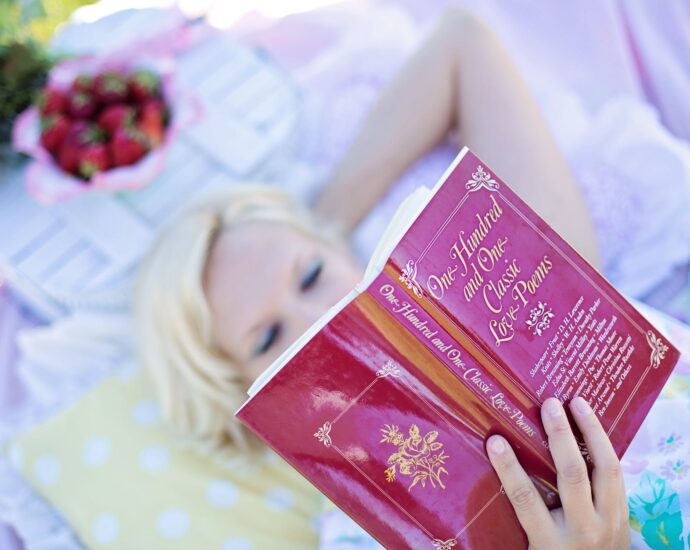 woman lying on bed while reading book