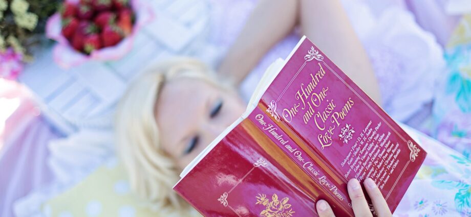 woman lying on bed while reading book