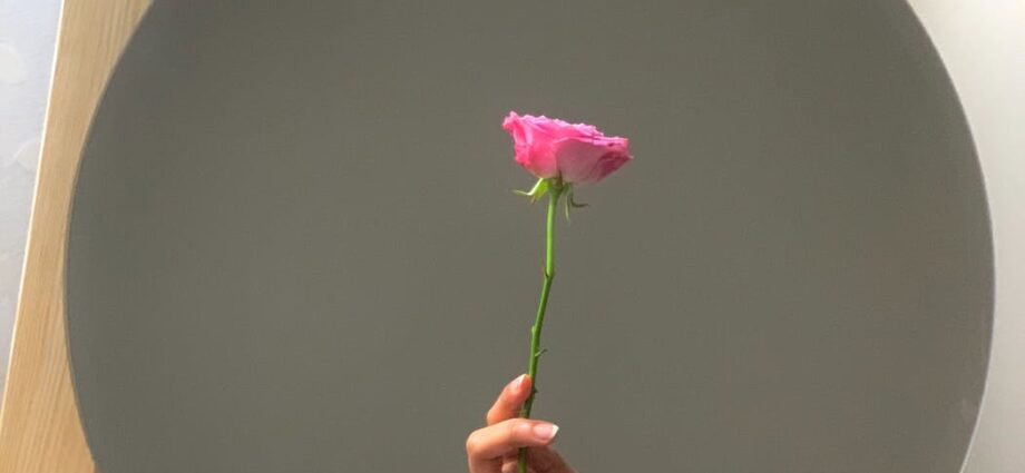 mirror reflecting tender hand with pink rose