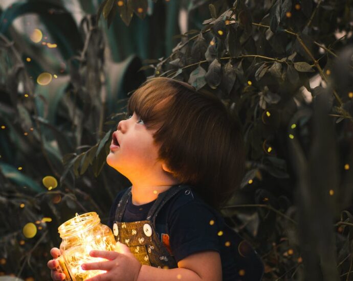 child holding clear glass jar with yellow light