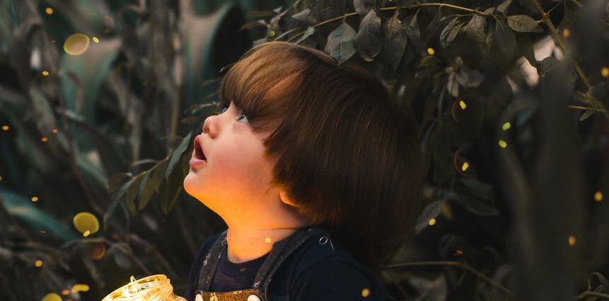 child holding clear glass jar with yellow light