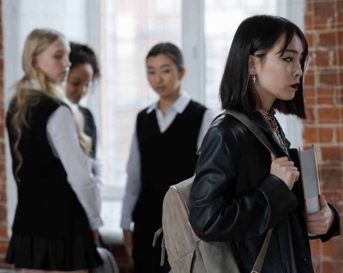 shallow focus of a girl in black leather jacket holding a book