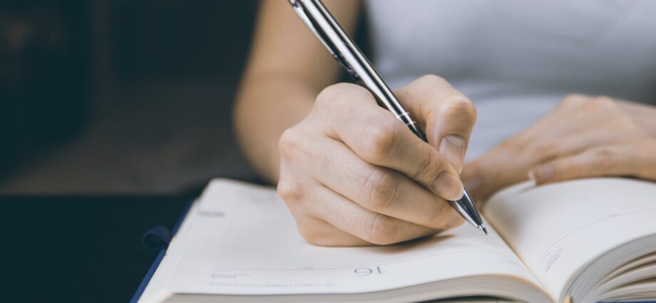photo of person writing on notebook